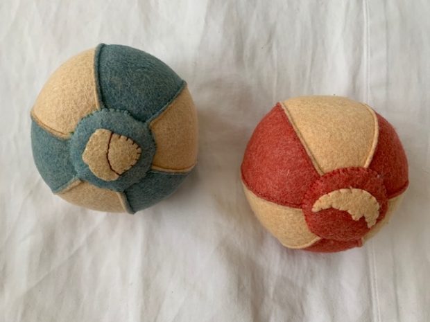 Two felt balls on white sheet. One ball is white and light blue and the other is white and red used during RIE® Parent Infant Guidance™ Classes